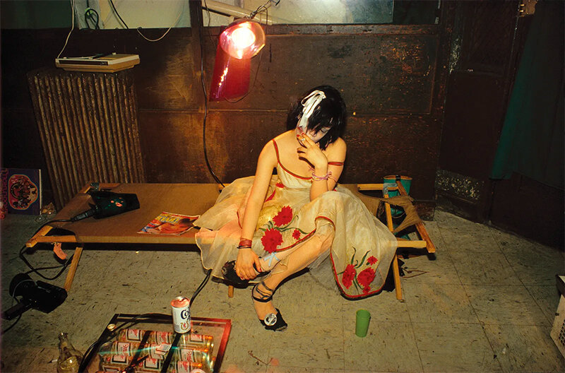 Nan Goldin image of a drug addict girl Trixie n a cot in a vintage party dress