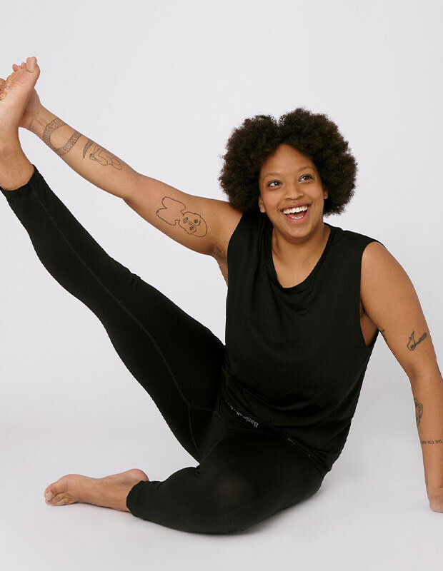 Woman stretching in black sleeveless tee and black leggings by Organic Basics