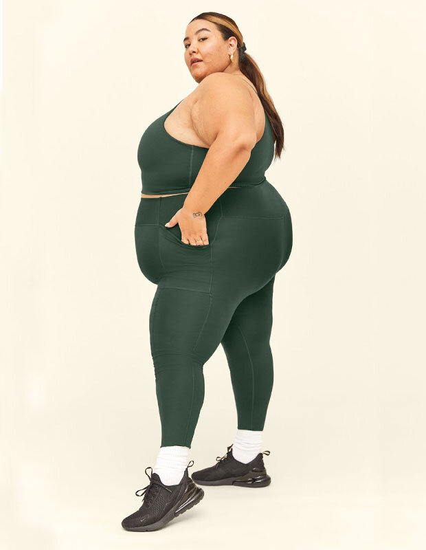 Woman wearing forest green leggings with pockets + top by Girlfriend Collective