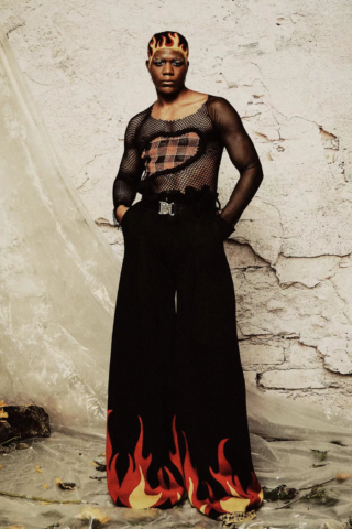 man in mesh shirt and wide leg pants with flames