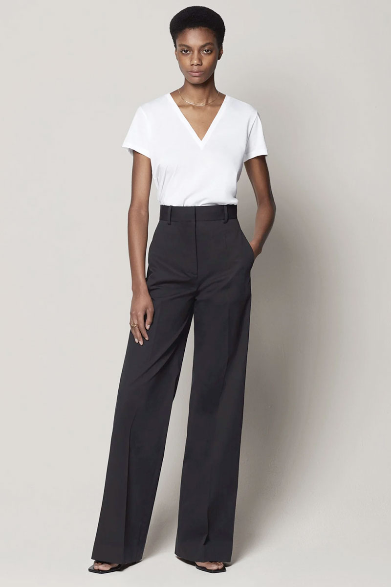 Another Tomorrow's classic flat front wide leg ethically produced trousers for women in black with a deep v-neck white t-shirt