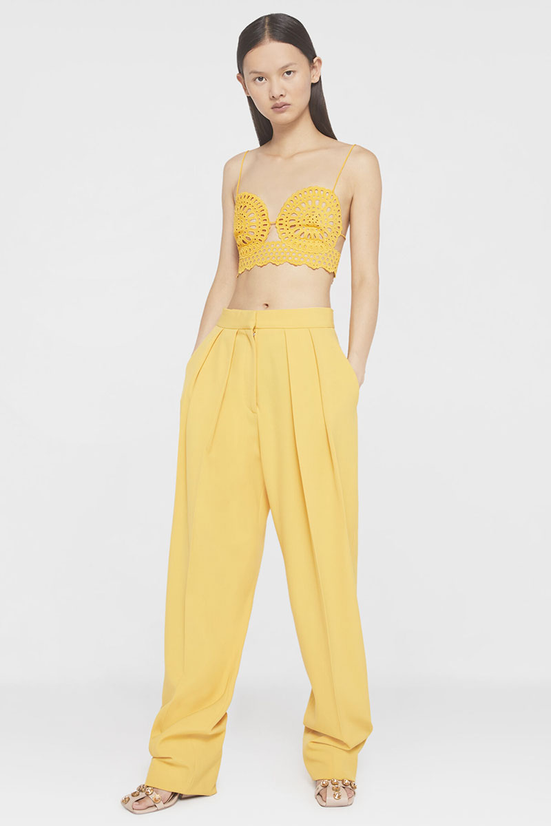 model in yellow Stella McCartney pleat front wideleg trousers and crochet bra top