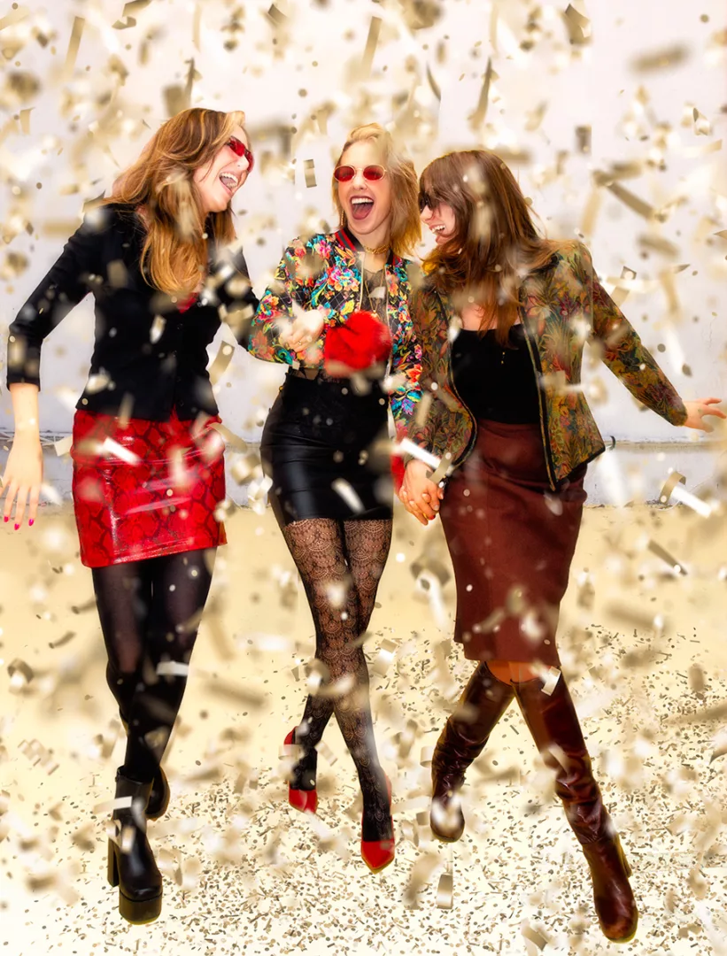 3 women walking through confetti wearing vintage