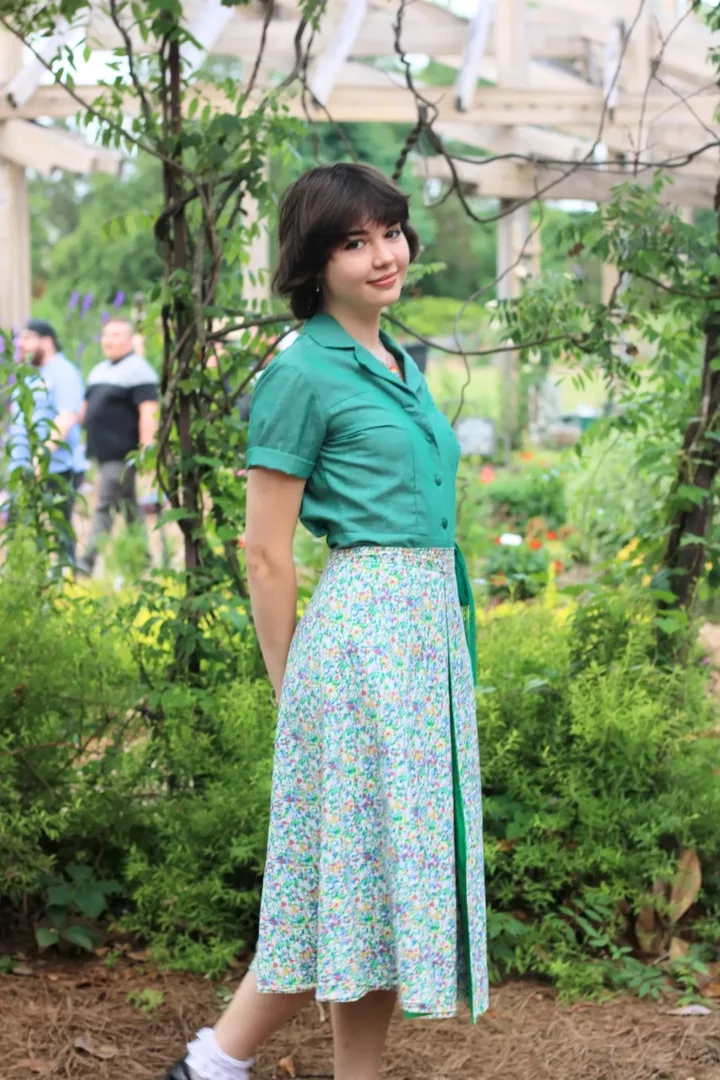 Harper Haynes wearing a girl scout uniform with a floral skirt over it