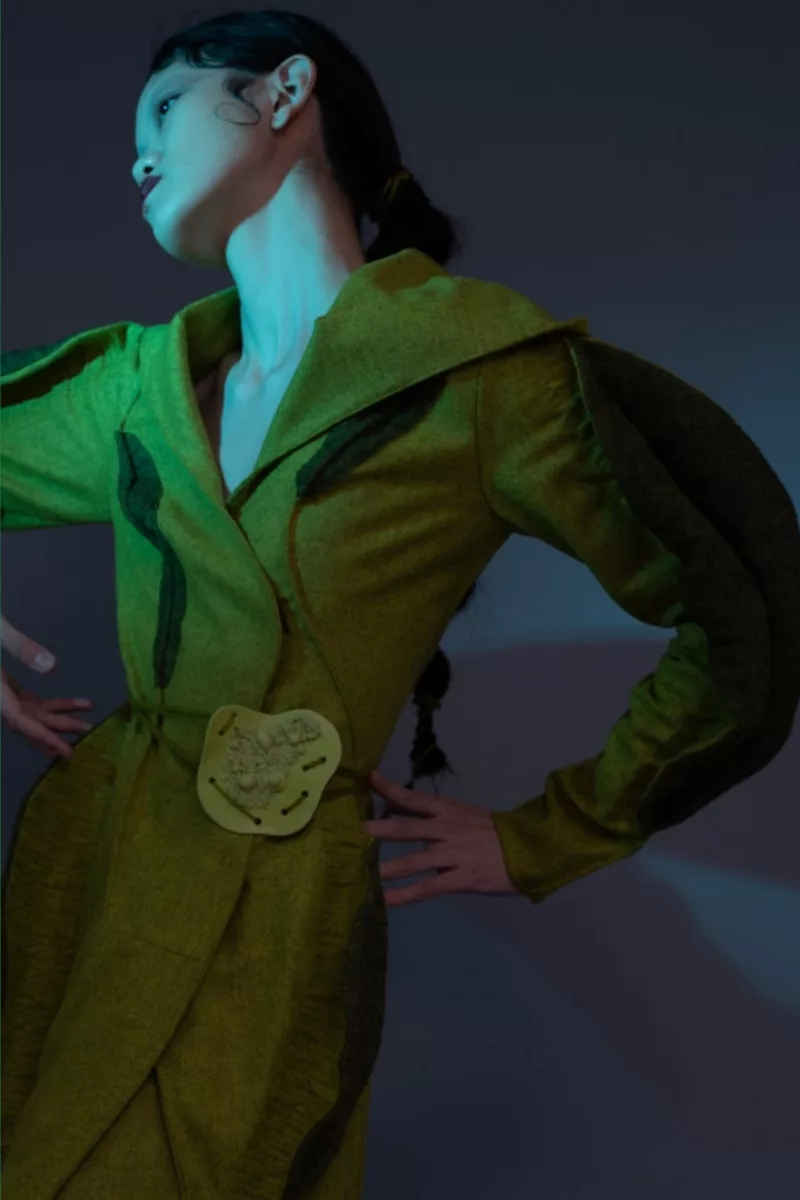 A model wearing green dress with cinched waist from Wenxin’s BFA thesis collection from Parsons fashion school