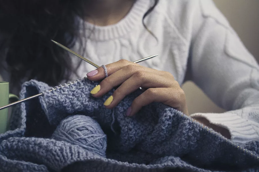 close up of hands knitting a sweater