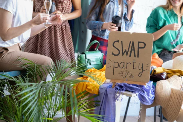 Young women at swap party. Casual clothes, shoes, hats, bags, jewellery. Idea of exchange your old wardrobe for new. Eco friendly cloth concept. Zero waste shopping, reduce and reuse, donation